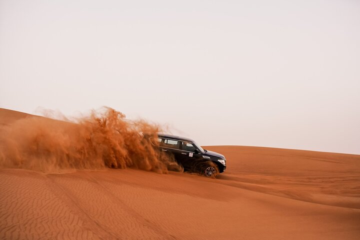 Experience the exhilarating rush of dune bashing in a 4x4 with golden sands flying as you conquer the breathtaking desert landscape creating unforgettable memories in Dubai's serene wilderness.